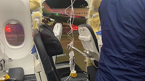 Passenger oxygen masks hang from the roof next to a missing window (Reuters)