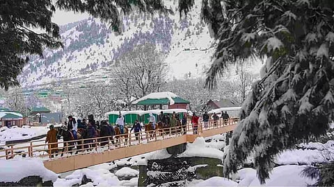 Tourists cross a bridge after snowfall at Sonamarg in Ganderbal district, Kashmir (PTI)