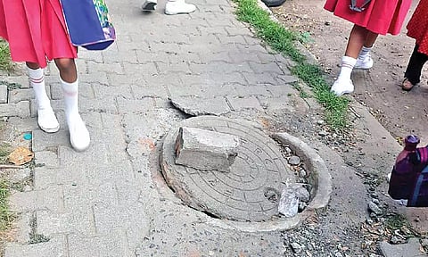 Schoolkids standing close to the broken manhole