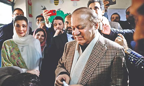 Former Prime Minister Nawaz Sharif smiles after casting his vote at a polling station