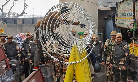 A worker installs barbed wire near the Tikri border in view of farmers' 'Delhi Chalo' march, near New Delhi on Tuesday. (PTI)