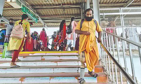 A disabled man struggling to climb the stairs at the Tambaram railway station