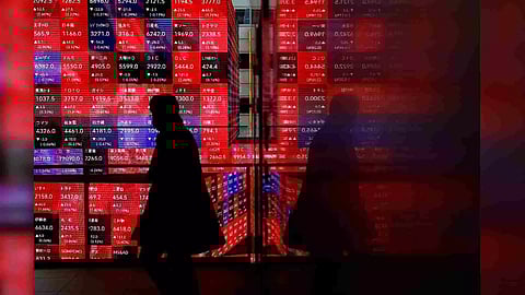 A visitor walks past Japan's Nikkei stock prices quotation board inside a building in Tokyo (Photo/Reuters)
