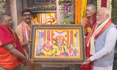 PM Modi being presented a portrait of the deity. IANS
