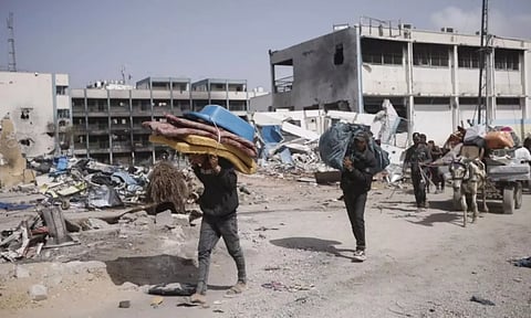 Palestinians carry their belongings after visiting their houses destroyed in the Israeli offensive on Khan Younis, Gaza Strip. AP