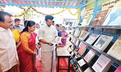 Minister Anbil Mahesh Poyyamozhi going through a book after inaugurating stalls in Tiruchy
