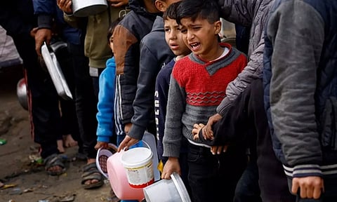 Palestinians wait to receive food amid shortages of food supplies, in Rafah in the southern Gaza Strip