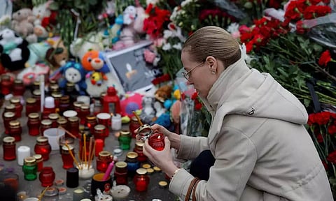 A woman lights a candle at a memorial to the victims of a shooting attack at the Crocus City Hall concert venue (Reuters)