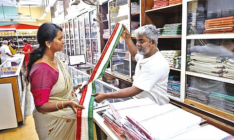 A salesman displaying an angavastram at Khadi showroom in Chennai