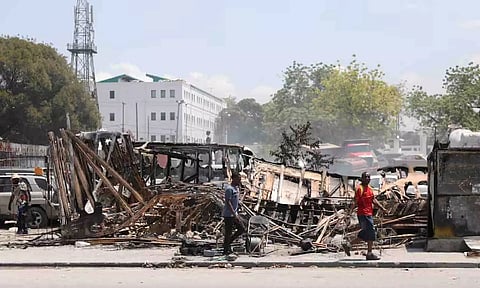 People walk past remains of vehicles near the presidential palace, after they were set on fire by gangs. (Reuters)