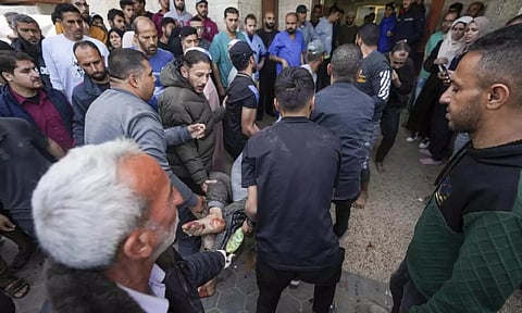 Palestinians carry a wounded person following an Israeli airstrike (AP)