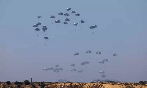 Humanitarian aid falls through the sky towards the Gaza Strip after being dropped from an aircraft (Reuters)