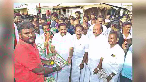 Edappadi K Palaniswami gives away a campaign pamphlet to a voter at Mattuthavani vegetable market in Madurai