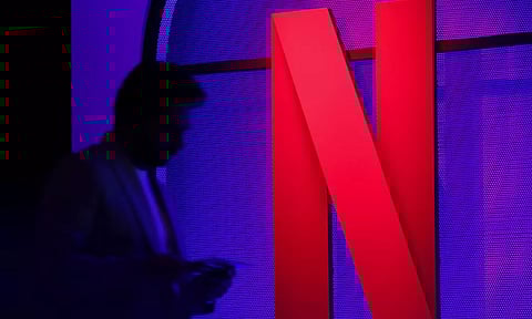 &nbsp;A man stands next to a logo of Netflix (Reuters)