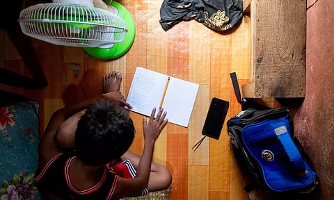 A student answers his learning module following the suspension of in-person classes, inside his house in Manila(Reuters)