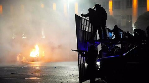 A police car on fire as riot police prepare to stop protesters in the center of Almaty, Kazakhstan, Wednesday, Jan. 5, 2022 (Photo/AP)