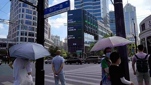 Pedestrians wait to cross a road at a junction near a giant display of stock indexes in Shanghai (Photo/Reuters)