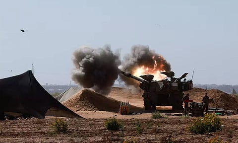 An Israeli military vehicle fires near the Israel-Gaza border (Reuters)