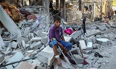 A wounded Palestinian sits on debris at the site of an Israeli strike on a house (Image : Reuters)