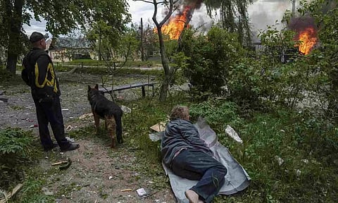 A man lies on the ground as he watches his burning house destroyed by a Russian airstrike (AP)