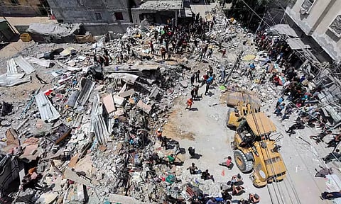 Palestinians gather as rescuers search for casualties trapped under the rubble of of a house hit in an Israeli strike (Reuters)