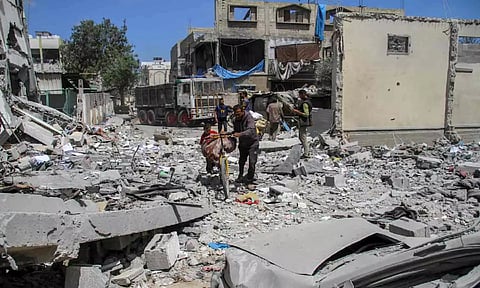 A Palestinian man pushes a bicycle with his belongings as he returns to his house at Zeitoun neighborhood after Israeli forces withdrew from the area following a raid, in Gaza City