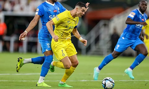 Cristiano Ronaldo is challenged for the ball by Ali al-Bulaihi of Al-Hilal