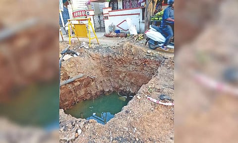 A two-wheeler passes through the narrow path alongside the pit