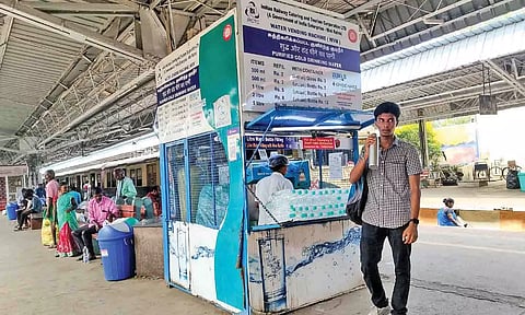 A stall selling drinking water at a railway station with prices displayed on the board