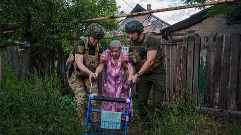 Police officers of the White Angels unit help an elderly woman walk into a van during an evacuation to safe areas (Photo: AP)
