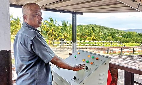 A staff operates electrical lifting barrier at Ayyalur level crossing gate