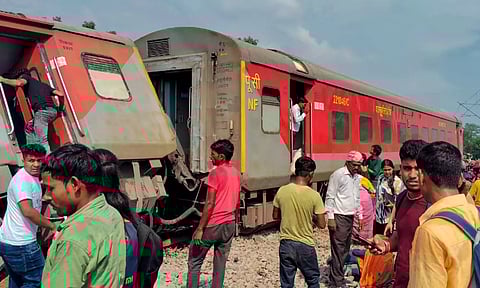 Passengers and locals near the derailed coaches of the Dibrugarh Express train after an accident, in Gonda district
