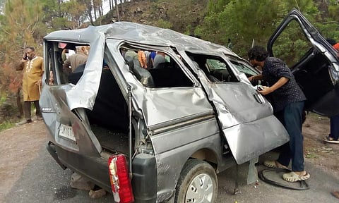 &nbsp;People gather near mangled remains of a vehicle after it rolled down a hilly road (PTI)