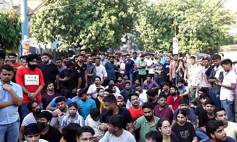 Security personnel interact with students protesting over the death of three civil services aspirants after the basement of a coaching centre was flooded by rainwater