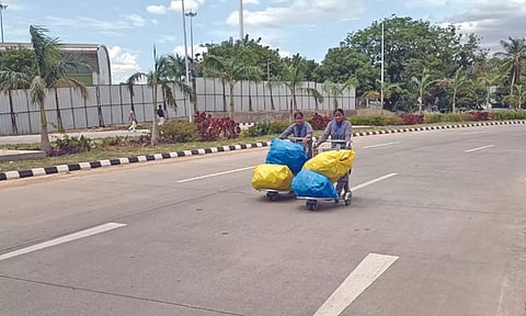 Cleanliness workers carry garbage collected at new terminal to the yard outside the airport