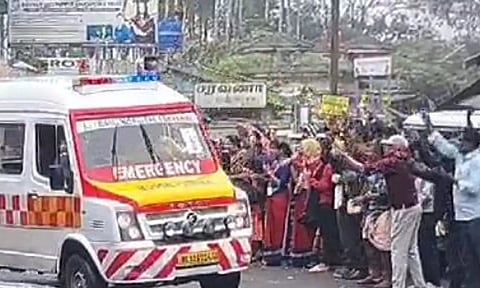 Residents pay floral tributes to an ambulance carrying the bodies of Wayanad landslide victims to the Nilgiris on Wednesday