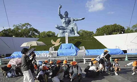 Visitors to the Peace Park crouch as an earthquake alert was issued in Nagasaki, western Japan (AP)