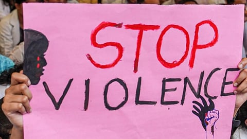 A placard denouncing violence against women being held at a protest march (PTI)