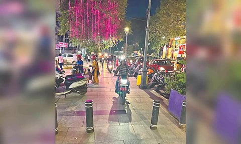 Two-wheelers being ridden and parked on the path meant for pedestrians