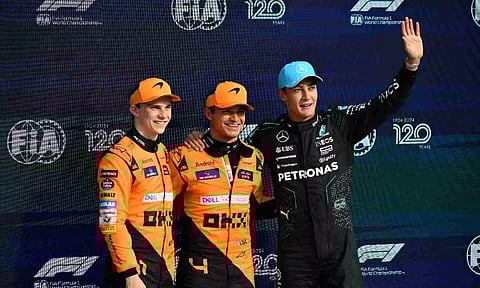 McLaren's Lando Norris (centre) celebrates his pole position next to second placed McLaren's Oscar Piastri (left) and Mercedes' George Russell after the qualifying session