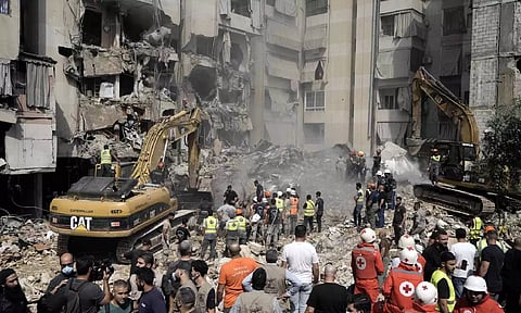 Emergency workers use excavators to clear the rubble at the site of Friday's Israeli strike in Beirut's southern suburbs