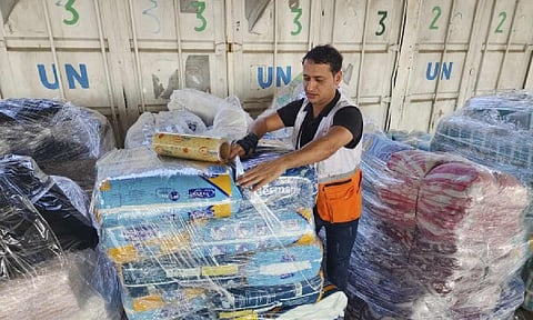 United Nations and Red Crescent workers prepare the aid for distribution to Palestinians at UNRWA warehouse in Deir Al-Balah
