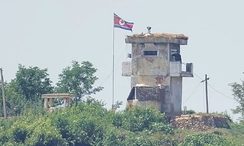 A North Korean soldier stands at the North's military guard post as a North Korean flag flutters in the wind, seen from Paju, South Korea (AP)