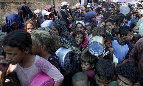 Palestinians line up for food distribution in Deir al-Balah, Gaza Strip