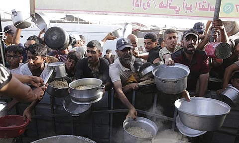 Palestinian men collect food aid ahead of the upcoming Eid al-Adha holiday in Khan Younis