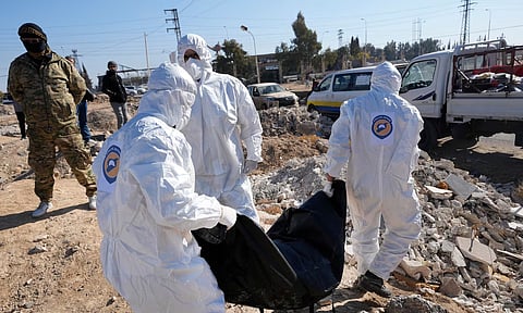 Syrian Civil Defense, carry one of several bodies and human remains that were found dropped at an open field on a road that links to Damascus international airport, in Damascus (AP Photo)