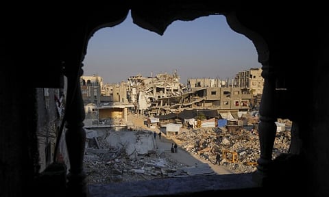 Palestinians walk through the destruction in the wake of an Israeli air and ground offensive in Khan Younis