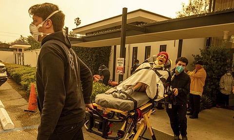 A resident is evacuated from a senior living facility as the Eaton Fire approaches (AP)