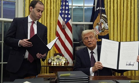 President Donald Trump holds up an executive order commuting sentences for people convicted of Jan. 6 offenses in the Oval Office of the White House (AP)