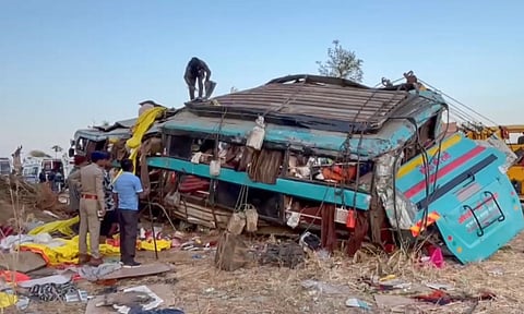 People gather near wreckage of a bus after it fell into a gorge, in Dang district